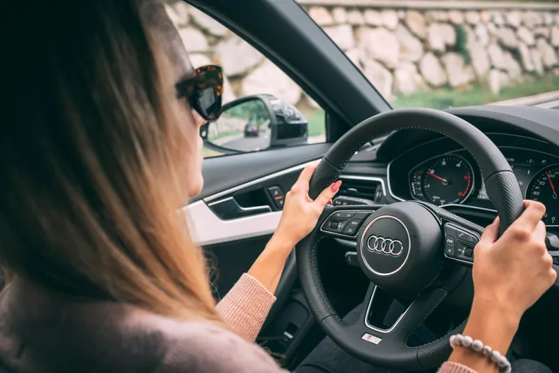 A woman driving, hands on the wheel